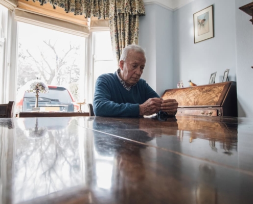 Abused elder sits alone at table in contemplation