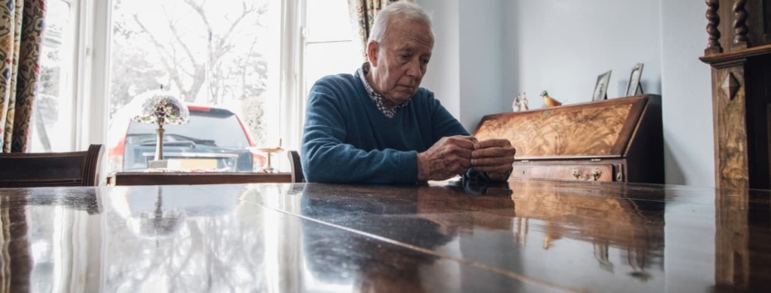 Abused elder sits alone at table in contemplation