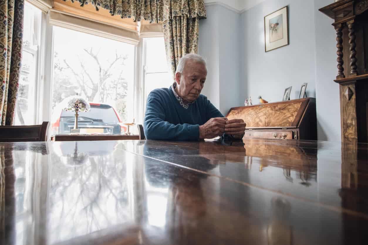 Abused elder sits alone at table in contemplation