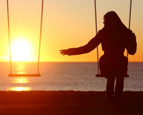 A bereft woman reaches for her missing loved one at sunset on the beach.