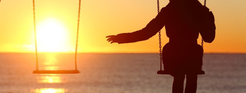 A bereft woman reaches for her missing loved one at sunset on the beach.