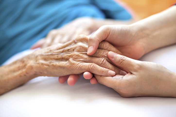 Nurse holding the hand of someone who is suffering elder abuse.