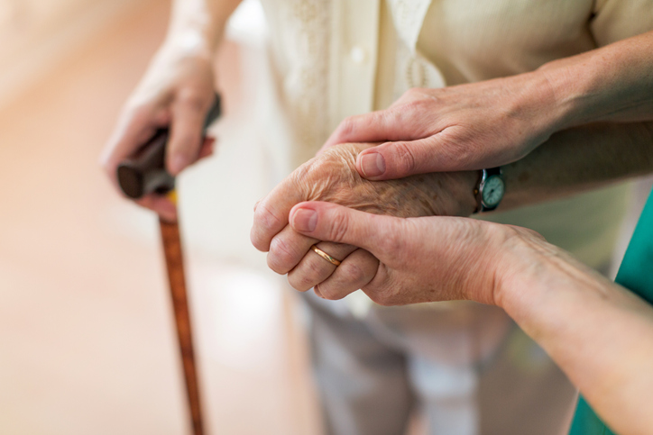 Nurse consoling her elderly patient by holding her hands. Call our Port St Lucie nursing home abuse lawyer today.