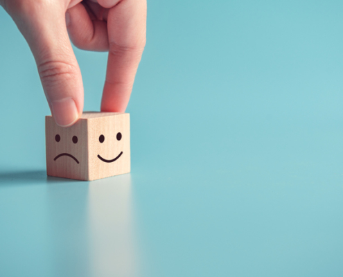 Close up customer hand choose smiley face and sad face icon on wood cube