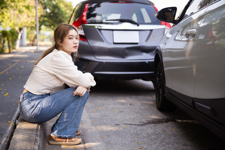 Woman sitting next to car accident scene - Fort Lauderdale car accident lawyer