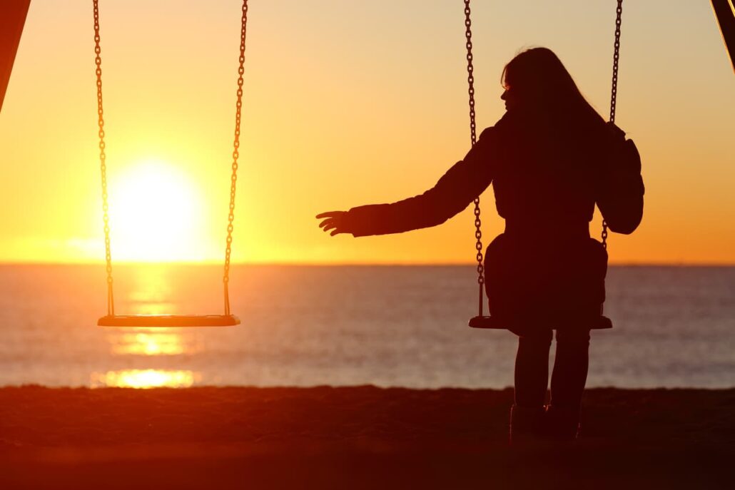 A bereft woman reaches for her missing loved one at sunset on the beach.