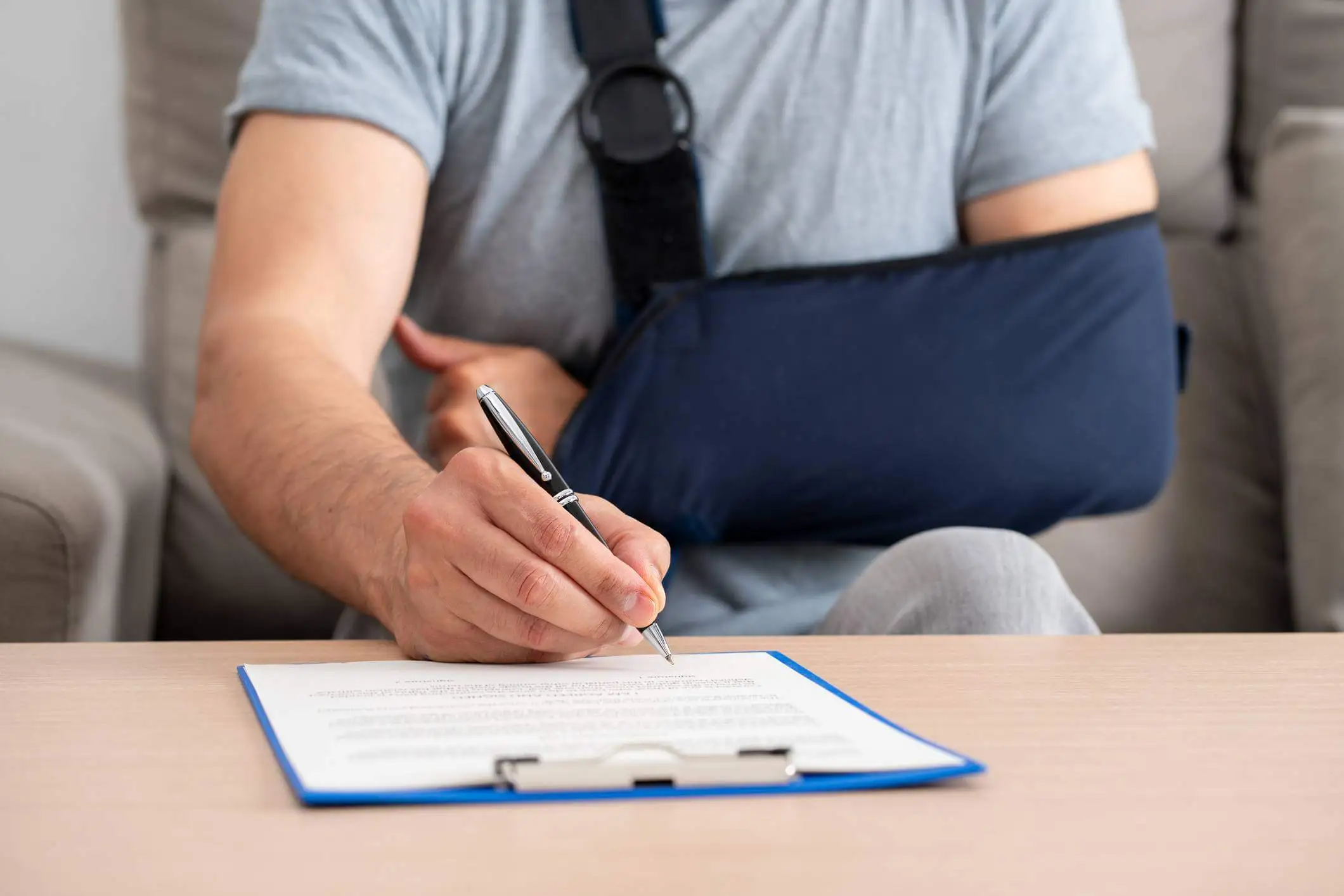 fort lauderdale personal injury lawyer - Front view of a handicapped man with sling signing contract at home