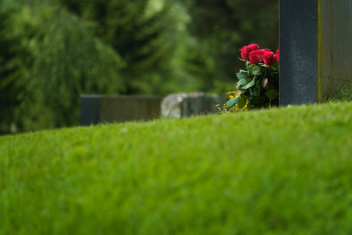 Red roses placed on a grave surrounded by grass - Palm Beach Gardens wrongful death lawyer