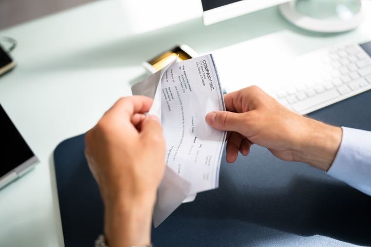 person opening envelope holding paystub - how your salary impacts your personal injury case