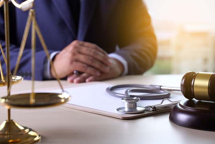 Man sitting with law gavel and stethoscope - the difference between medical malpractice and professional indemnity